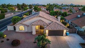 A single-story house with a tiled roof, a front entrance with a gate, and a driveway leading to a garage. - Luxury Scottsdale Retreat! Heated Pool | Mini Golf (Scottsdale)