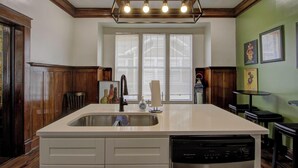 Una cucina con un'isola grande, mobili in legno, una lavastoviglie e una finestra con persiane.