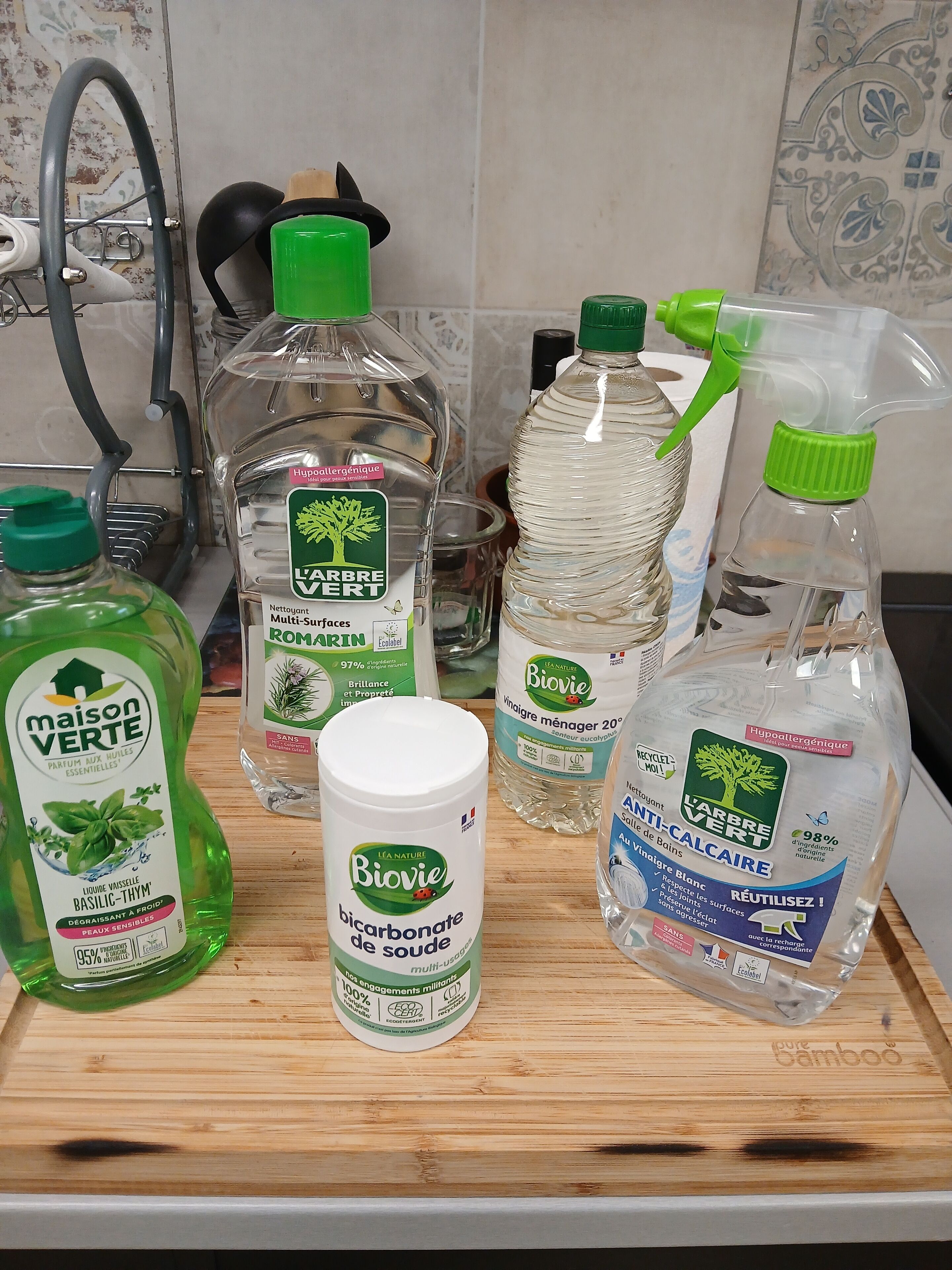 A kitchen counter with various cleaning products including bottles and a spray bottle.
