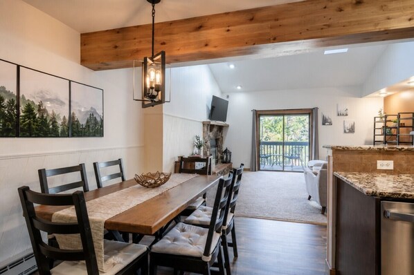 A dining area with a long wooden table, cushioned chairs, and a hanging light fixture.