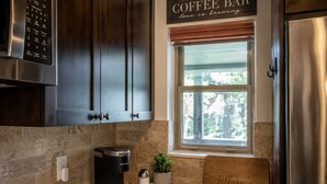 A kitchen with a coffee maker, a window with a view, and a sign that reads 'COFFEE BAR love is brewing'. - Mountain Views from WP Top Floor Getaway (Winter Park)