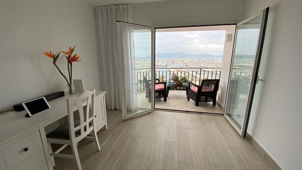 Un balcón con vista a un puerto deportivo y montañas.