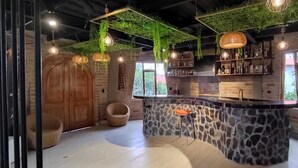 A bar area with a stone counter, wooden door, and hanging lights.