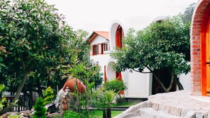 A courtyard with a stone staircase, a white building with red accents, and lush greenery.
