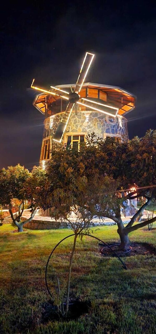 A windmill with a stone exterior and illuminated interior at night.