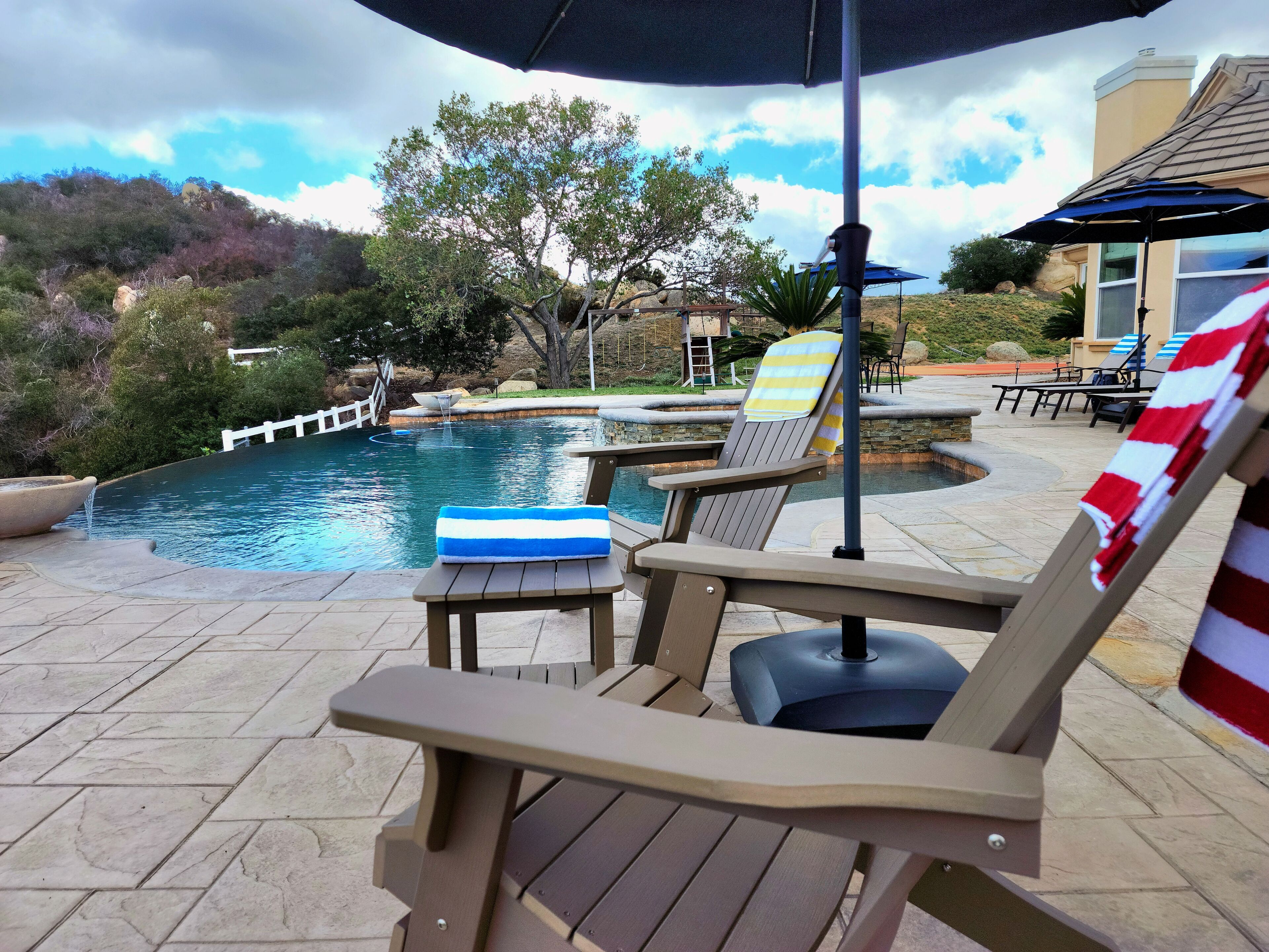 A poolside area with lounge chairs, a table, and an umbrella.