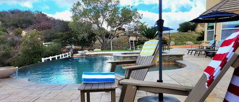 A poolside area with lounge chairs, a table, and an umbrella.