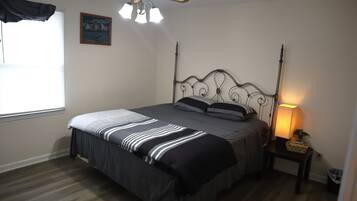Ein Schlafzimmer mit Bett, Deckenventilator, Nachttischlampe und einem Fenster mit Jalousien.