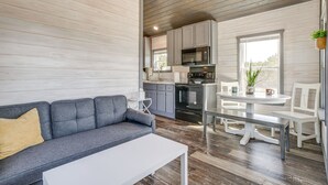 A modern kitchen with grey cabinets, a white dining table, and a grey sofa.