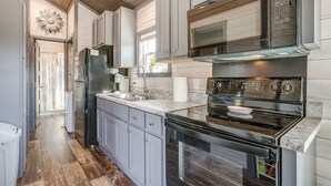 Una cocina moderna con gabinetes grises, estufa de acero inoxidable y horno empotrado.