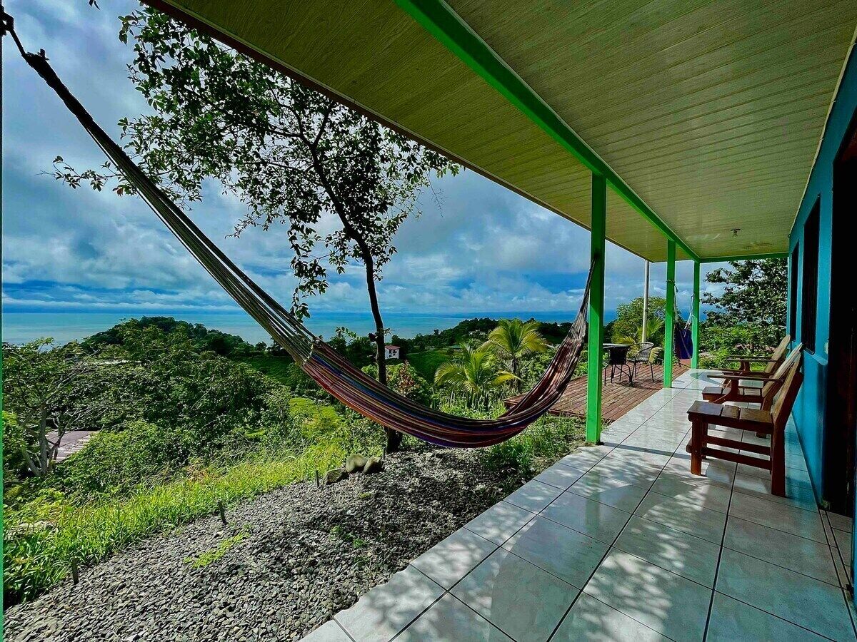 A hammock on a porch overlooking a lush landscape.
