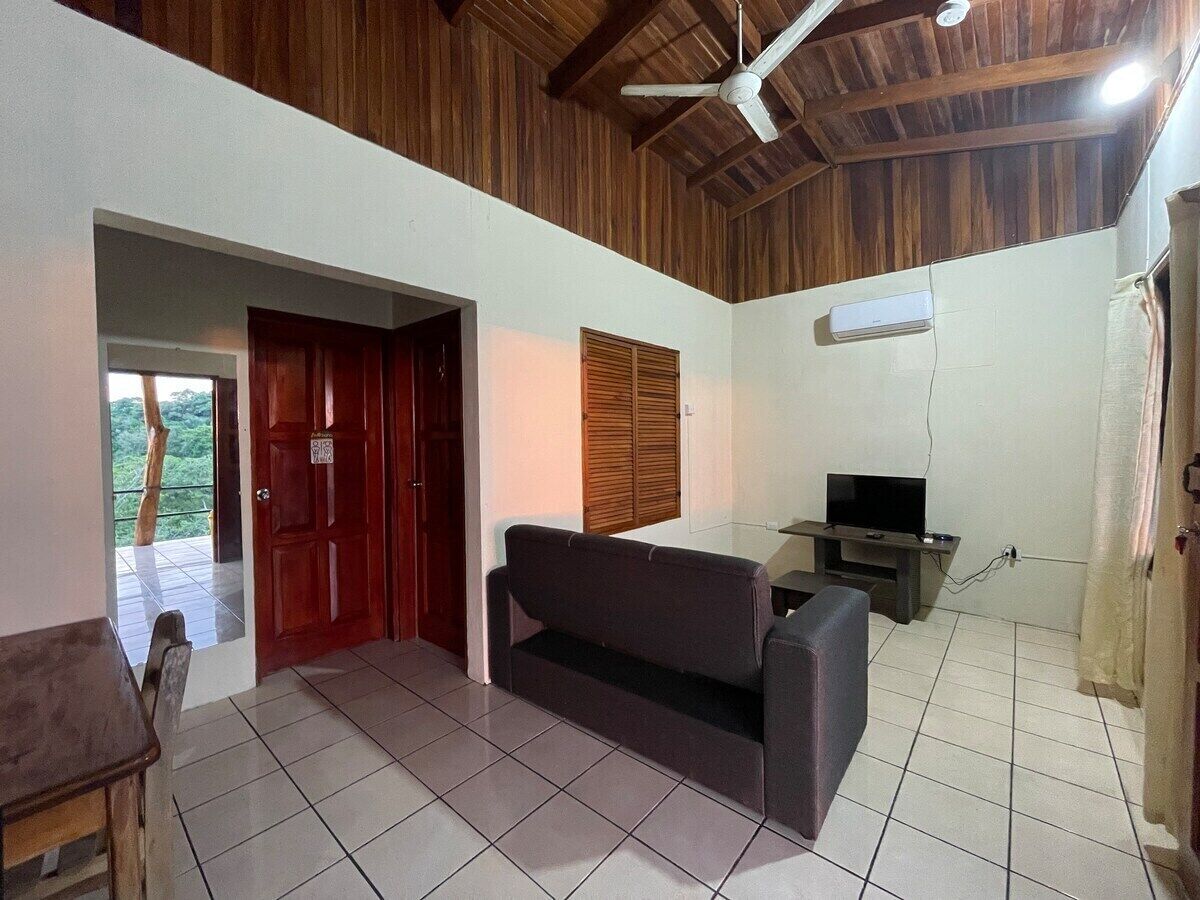 Una sala de estar con sofá, televisión y ventilador de techo.