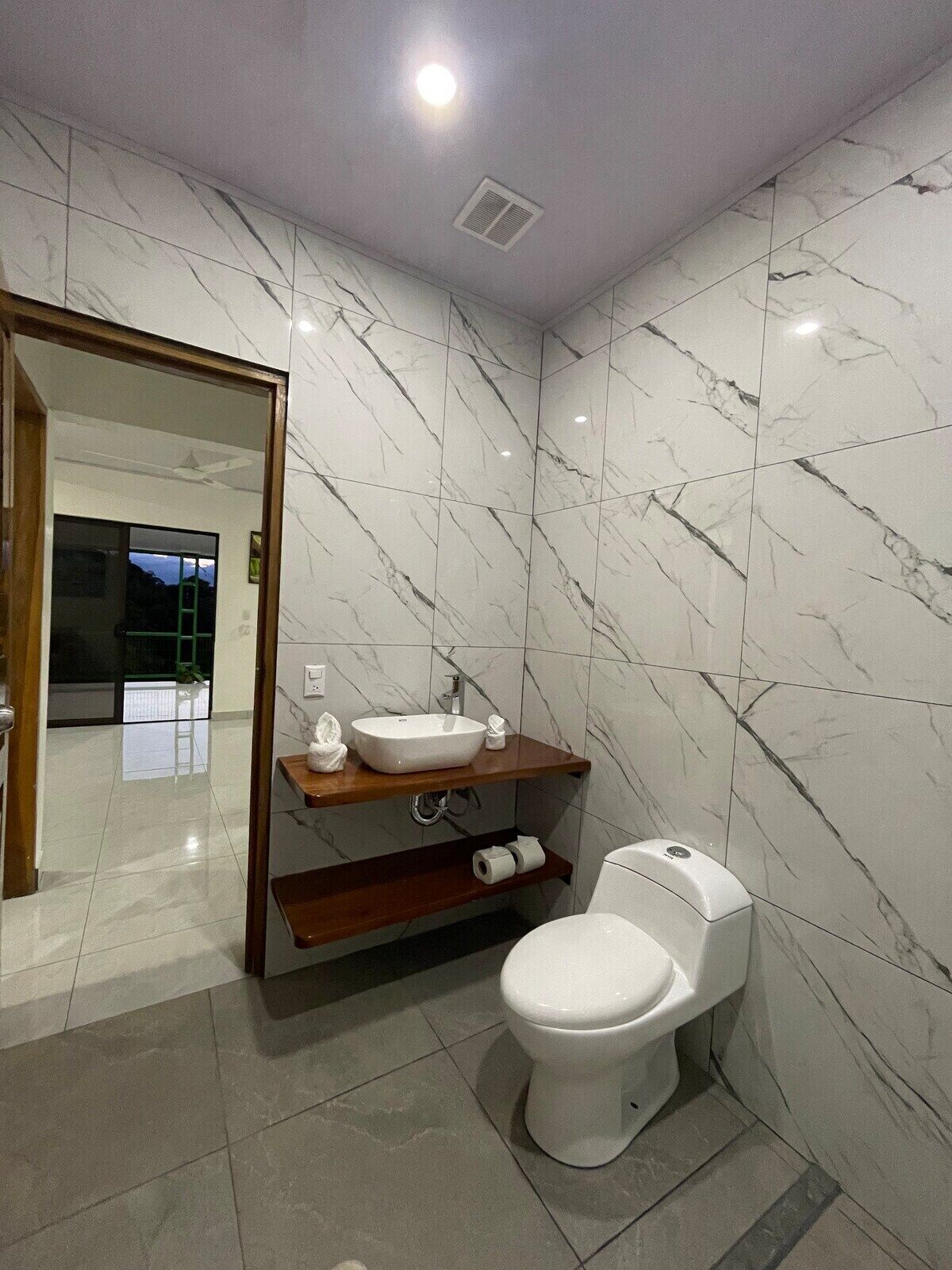 Un baño moderno con inodoro blanco, tocador con lavabo y espejo.