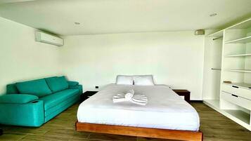 Une chambre d’hôtel moderne avec un grand lit, un canapé de couleur turquoise et une bibliothèque intégrée.