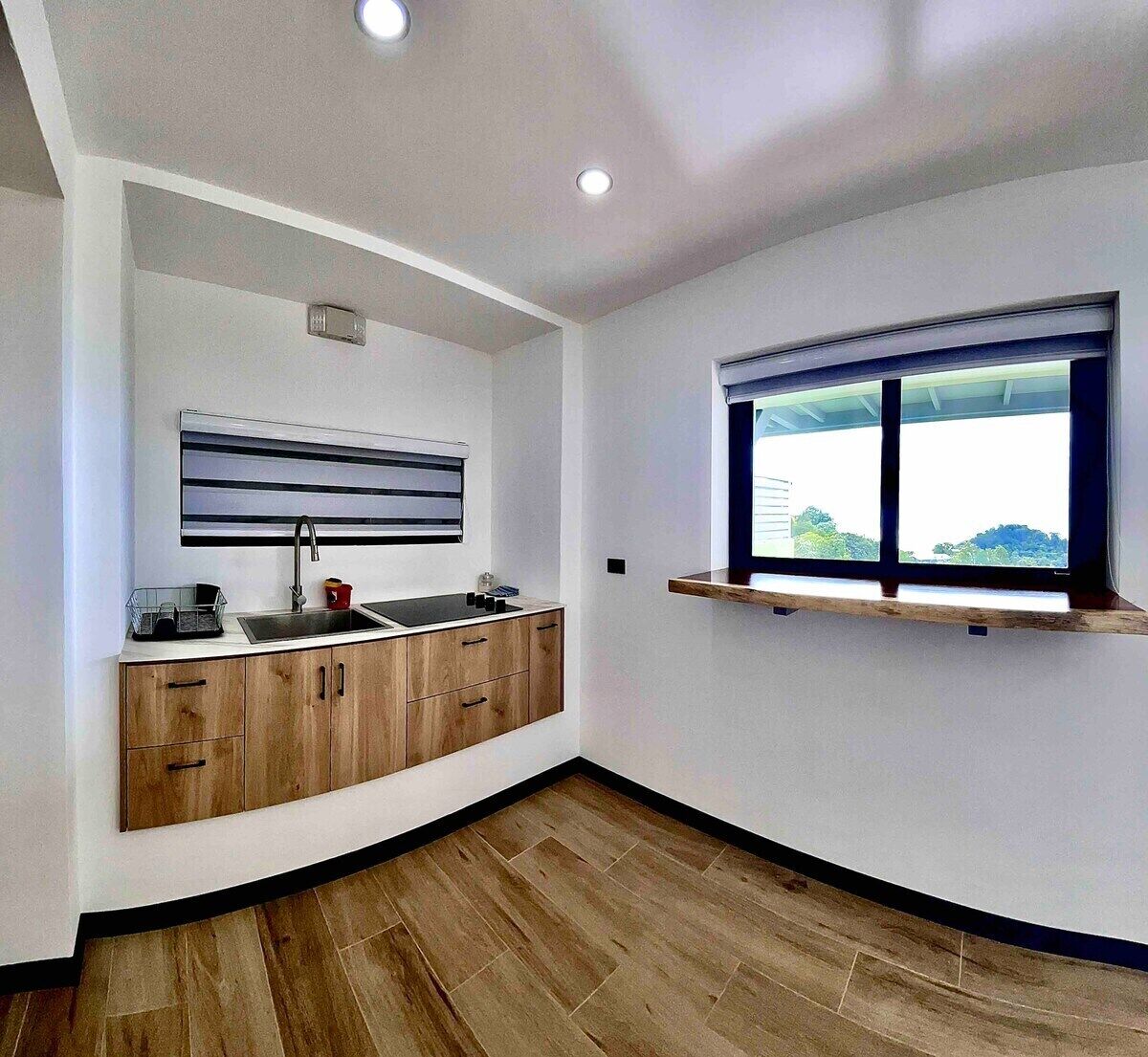 A modern kitchen with a built-in sink, wooden cabinets, and a window with a view.