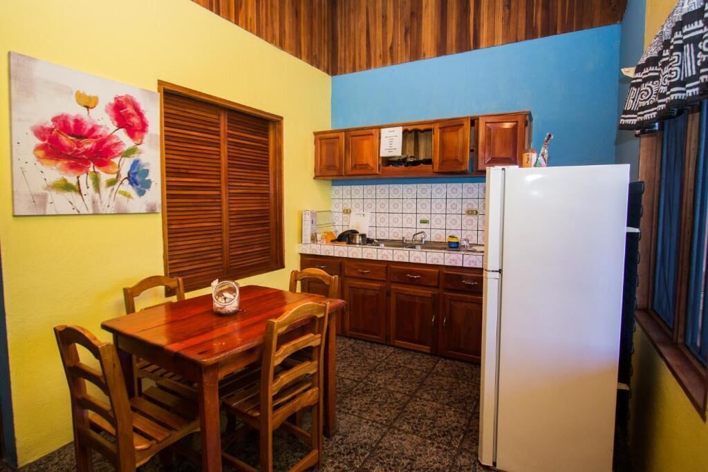 A kitchen with wooden cabinets, a white refrigerator, and a dining table with chairs.