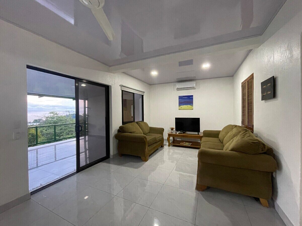 Amplia sala de estar con dos sofás, un televisor y un balcón con vistas.