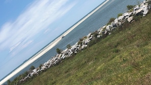 Un paysage côtier caractérisé par une côte rocheuse, des zones herbeuses et une vue dégagée sur l’océan.