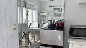 Une cuisine compacte équipée d’un réfrigérateur en acier inoxydable, d’un four à micro-ondes et d’un mixeur posés sur le plan de travail.
