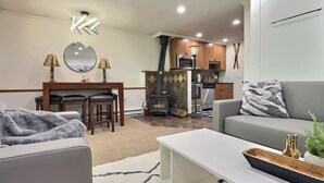 A modern living room with a sofa, coffee table, and a dining area with chairs and a table.