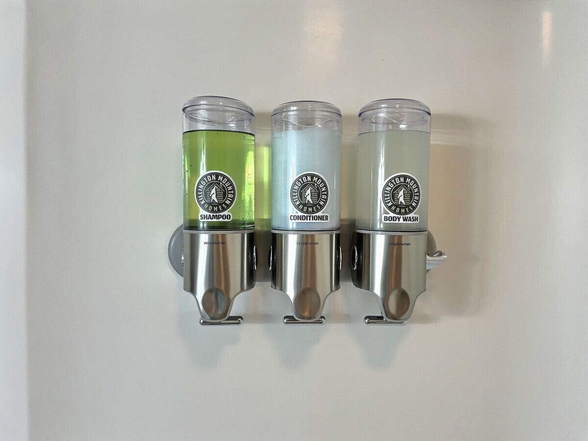 Three bottles of lotion on a wall.