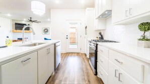 A modern kitchen with white cabinetry, a stainless steel sink, and a built-in oven. - Chic New Build - 5 miles to Tech/Covenant/UHC - 2 miles to shopping! (Lubbock)