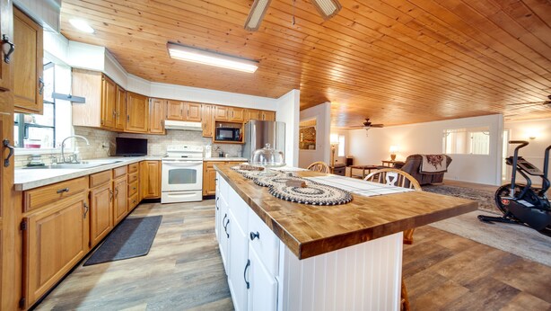 Eine moderne Küche mit Holzschränken, einer zentralen Kochinsel und einem Essbereich mit Tisch und Stühlen.