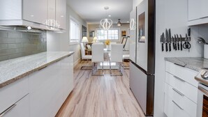 A modern kitchen with white cabinetry, a granite countertop, and a central island. There are hanging knives and a ceiling fan visible. - 2 Blocks to Riviera Beach: Upscale Condo w/ Patio (West Palm Beach)