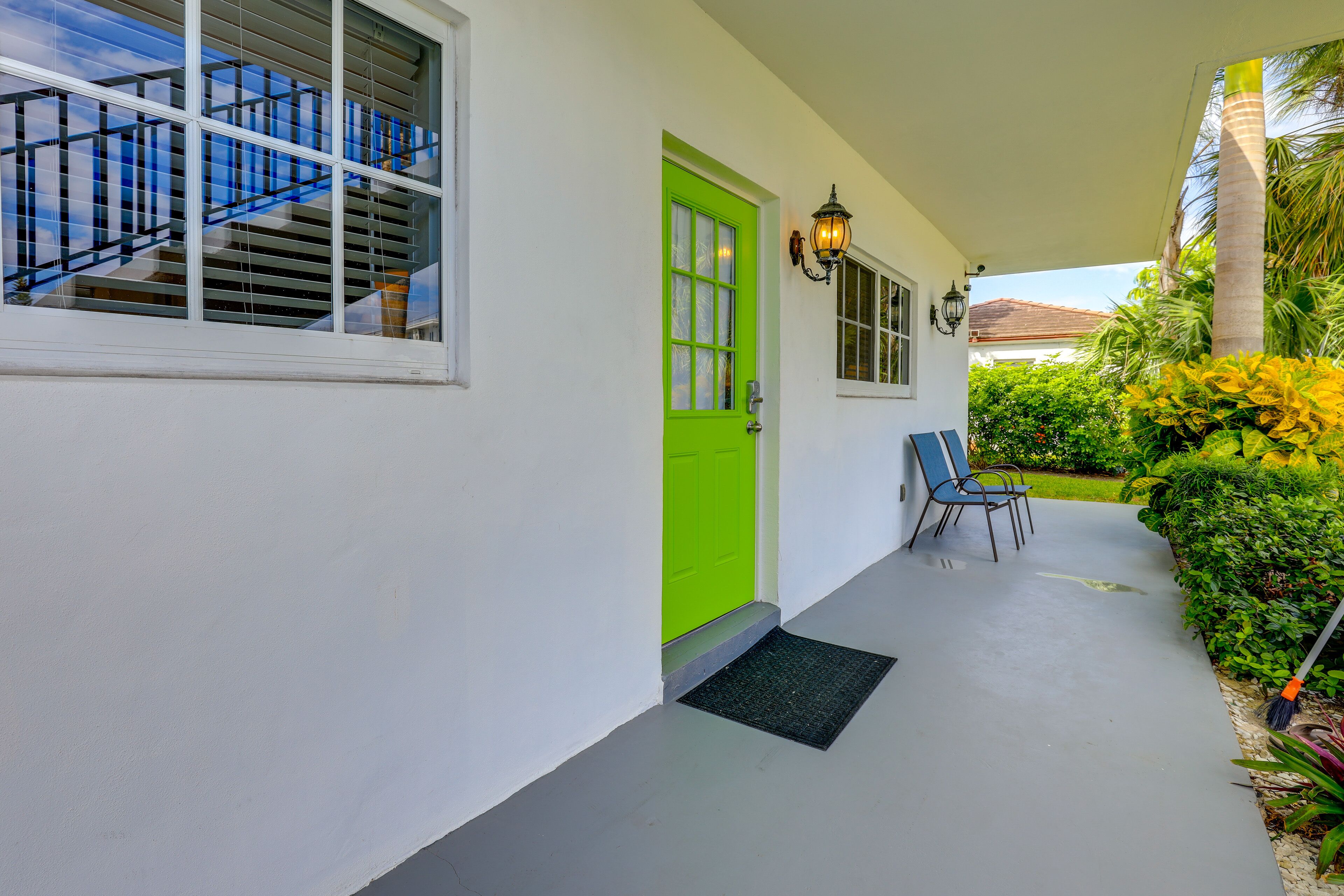 A covered porch with a green door, a staircase, and a chair.