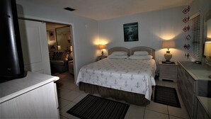 Quarto com cama, abajures, mesa de cabeceira, cômoda e televisão.