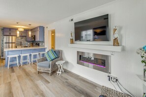 Une cuisine moderne dotée d’un coin bar, d’un téléviseur à écran plat fixé au mur et d’une cheminée située en dessous.