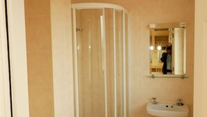 Ein Badezimmer mit einer Duschkabine, einem Standwaschbecken und einer Toilette.