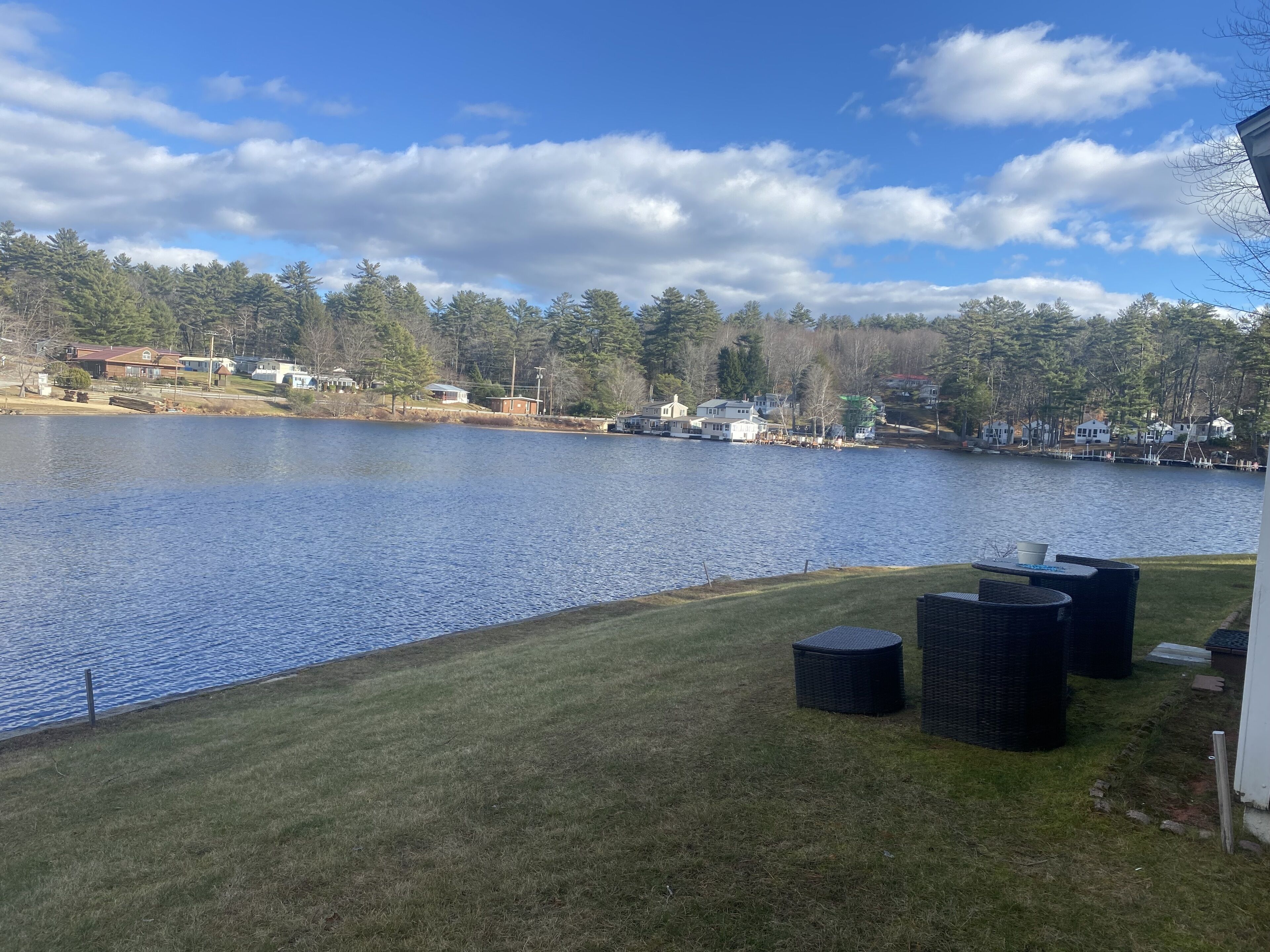 A lakeside view with a grassy area and outdoor furniture.