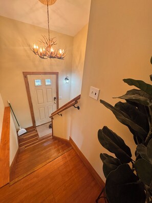 A wooden staircase with a handrail, a door at the top, and a wall-mounted light fixture.