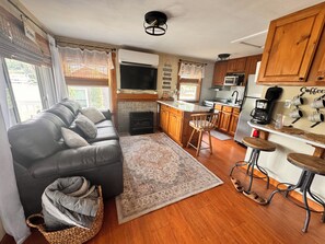 A cozy living area with a sofa, a fireplace, and a kitchen with wooden cabinets and a bar.