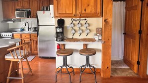 Una cocina con armarios de madera, microondas, cafetera y una barra de café con tazas.