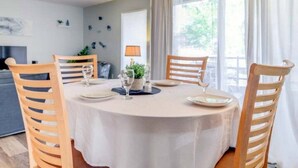 Un comedor con una mesa redonda preparada para cuatro personas, rodeada de sillas de madera.