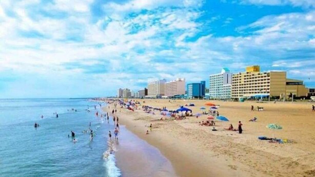 Una playa con gente, sombrillas y edificios al fondo.