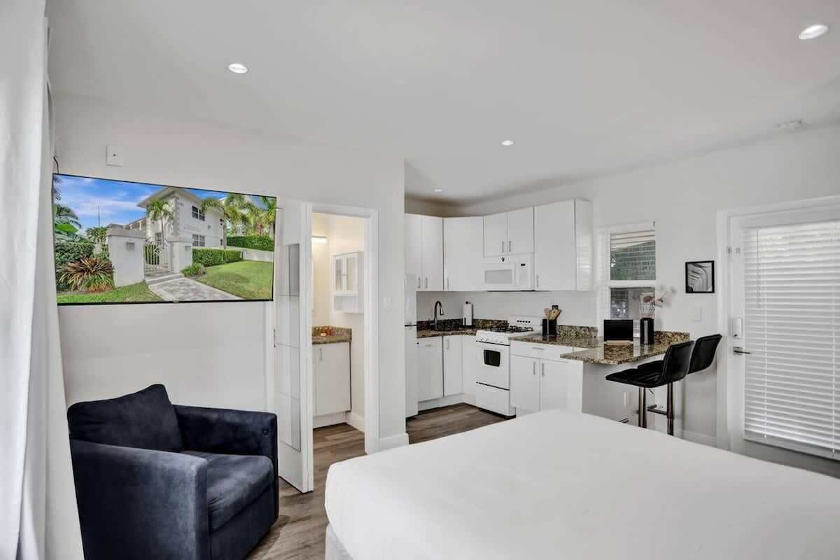 A modern kitchen with white cabinets, a countertop, and a dining area with a white table and black chairs.