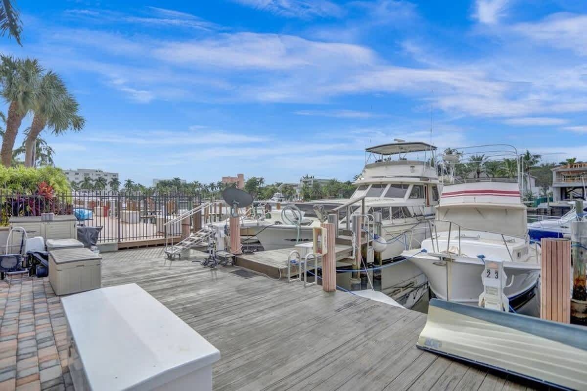 A marina with multiple boats docked, a wooden deck, and a small outdoor seating area.