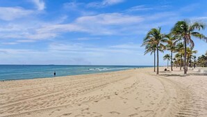 Una playa arenosa con palmeras y un cielo azul despejado.