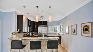 A modern kitchen with granite countertops, stainless steel appliances, and bar stools. - Modern 1BR on 2nd Floor Near Las Olas (Fort Lauderdale)