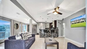 A modern living room with a sofa, a coffee table, and a kitchen area in the background. - Modern 1BR Waterfront Stay w/ Patio | Las Olas (Fort Lauderdale)