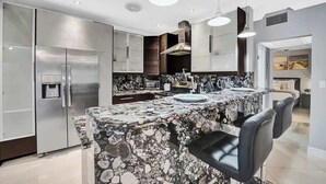 A modern kitchen with a granite island, stainless steel appliances, and pendant lighting. - Modern 1BR Waterfront Stay w/ Patio | Las Olas (Fort Lauderdale)