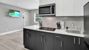 A modern kitchen with a built-in microwave, stainless steel sink, and black cabinets.