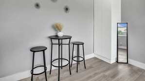 A modern room with a grey wall, a round table with two stools, and a tall mirror.