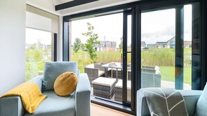 Un salon moderne avec un canapé et une table à manger, de grandes portes-fenêtres coulissantes donnant sur un jardin.