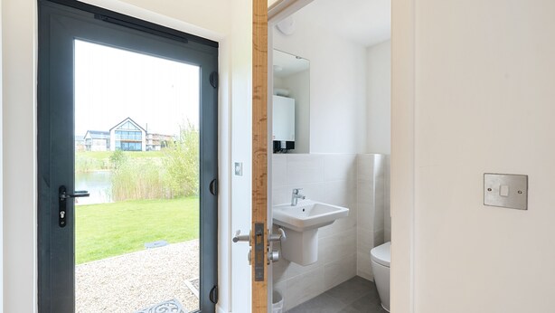 Une salle de bain moderne équipée d’un lavabo, de toilettes et d’une porte donnant sur un balcon.