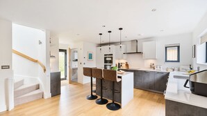 Une cuisine moderne dotée d’un îlot central, de tabourets de bar et de luminaires suspendus.