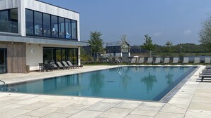 Ein modernes Gebäude mit Schwimmbad, Liegestühlen und blauem Himmel.